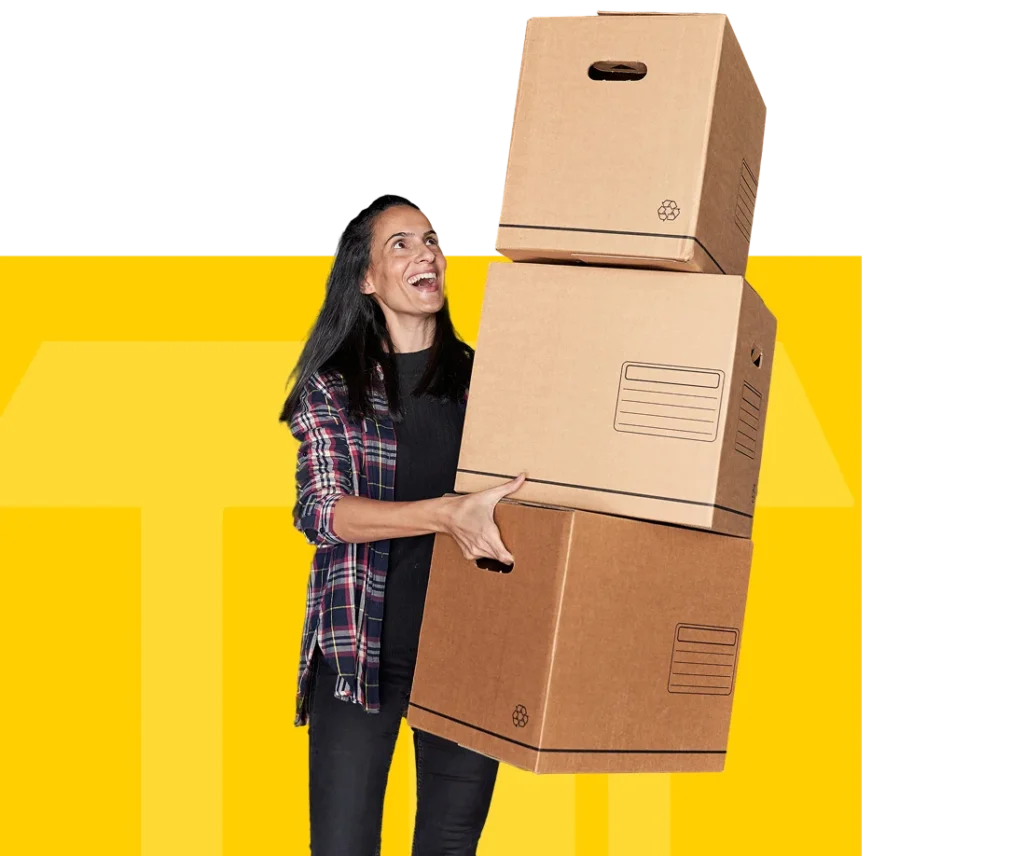 mujer-positiva-mirando-hacia-arriba-mientras-lleva-un-monton-de-cajas-de-carton-con-pertenencias-personales-cerca-de-almacenamiento-cerrado-durante-el-dia-de-la-mudanza 1